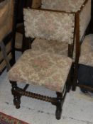 A set of four early 20th Century oak framed dining chairs with cream ground florally decorated