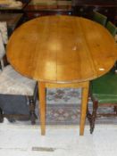 An elm drop-leaf wake style table, raised on square tapered legs,
