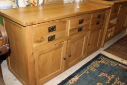 A light oak sideboard with three drawers above three cupboard doors