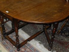 An early 20th Century oak gate-leg dining table with baluster turned supports and stretchered base