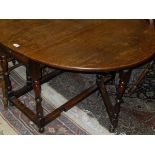 An early 20th Century oak gate-leg dining table with baluster turned supports and stretchered base