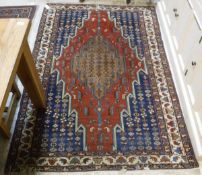 A Caucasian rug, the central panel set with floral decorated graduated medallions on a blue,