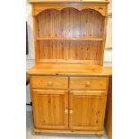 A 20th Century pine dresser with open shelves above two drawers and two cupboard doors on turned