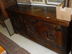 A large oak sideboard with three heavily carved cupboard doors with central patterned roundels and