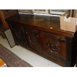 A large oak sideboard with three heavily carved cupboard doors with central patterned roundels and