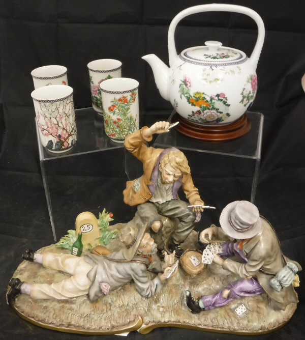 A Continental figural group of three gentlemen playing cards on a tree stump,