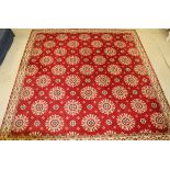 A red ground Axminster carpet with all over floral motifs in red and creams within a stepped cream