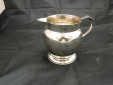 A George V silver jug of bellied form raised on a circular foot (London 1920)