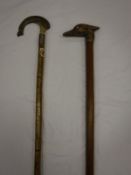 Two walking staves, one with a carved horn finial in the shape of a salmon,