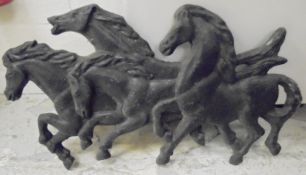 A painted cast metal horse plaque depicting four horses racing,