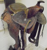 A leather Buffalo Western saddle with embossed decoration and leather stirrups
