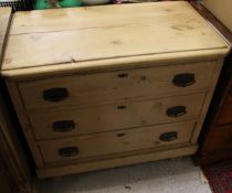 A Victorian pine chest of drawers the plain top above three drawers with metal handles raised on bun