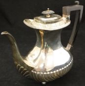 A late Victorian silver coffee pot with gadrooned belly raised on four bun feet (London 1899 by