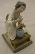 A Lladro figure of a Japanese girl tending a flower in a vase, No'd. to base "J-27N"