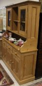 A 20th Century pine kitchen dresser with open shelves flanked by glazed cupboard doors on a base of