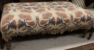 A Victorian style foot stool of rectangular form with floral decorated upholstery raised on ringed