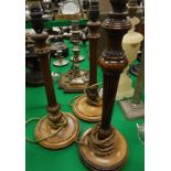 A pair of early 20th Century mahogany table lamps of reeded column form, together with another