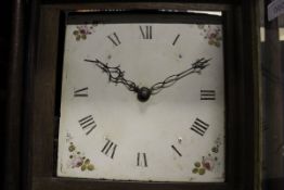 An oak cased long case clock with Roman numerals to the enamel dial and floral sprays to the