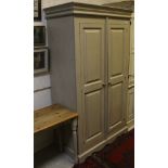 A modern painted pine two door wardrobe, the moulded top above two doors opening to reveal a hanging