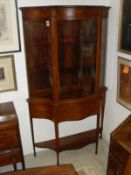 An Edwardian mahogany and inlaid display cabinet, the glazed top of serpentine form,