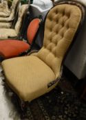 A Victorian rosewood framed spoon back nursing chair with pale gold upholstery, button back and