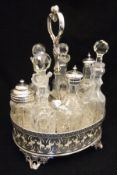 A silver plated and cut glass seven bottle cruet, two copper saucepan lids, three copper cylindrical