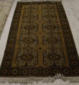 A golden Afghan rug, the central panel set with two rows of five square medallions on a plain golden