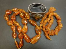 A bag containing two amber necklaces, one with polished beads, the other chipped, an amber effect