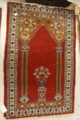 A Persian prayer rug, the central panel set with an urn of flowers, within a columned archway, on
