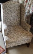 A 19th Century wing back armchair with mahogany frame in a pale cream and floral decorated