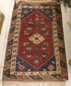 A Caucasian style rug, the central panel set with a diamond-shaped medallion on a burgundy and