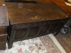 An 18th Century oak coffer, the panel top opening to reveal a plain interior above a carved front