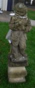 A composite stone figure statue of a boy in a coat on a baluster shaped base