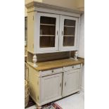 A painted pine dresser with moulded pediment above the two glazed doors enclosing shelves, raised on