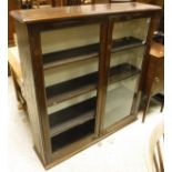 A Victorian oak dining table on carved and fluted legs to castors and a mahogany two door bookcase