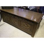 A 20th Century oak coffer with carved panels and sides, together with a similar carved oak