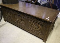 A 20th Century oak coffer with carved panels and sides, together with a similar carved oak