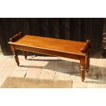 A mahogany window seat in the Victorian manner with scroll handles, raised on turned and reeded