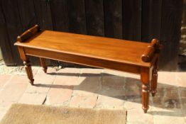 A mahogany window seat in the Victorian manner with scroll handles, raised on turned and reeded