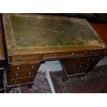 A Victorian oak pedestal desk with green leather inset top above nine assorted drawers, raised on