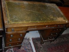 A Victorian oak pedestal desk with green leather inset top above nine assorted drawers, raised on