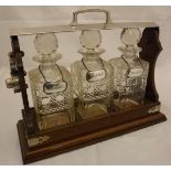 An oak and plated tantalus containing three hobnail cut glass decanters and stoppers and three