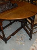 An early 20th Century oak gate-leg dining table with baluster turned supports and stretchered base