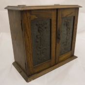 A circa 1900 oak smokers cabinet with beaten copper doors enclosing a basic fitted interior with