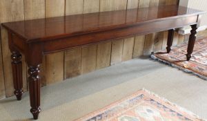A long mahogany window seat with cleated end supports to four turned and reeded legs