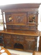 A late Victorian carved oak Gothic Revival sideboard with mirrored superstructure and cupboard door,