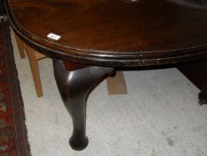 An Edwardian mahogany extending dining table on cabriole legs with extra leaves and a winder