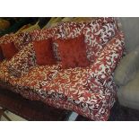 A pair of two seat sofas upholstered in cream with red foliate pattern,