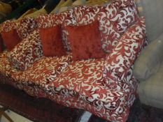 A pair of two seat sofas upholstered in cream with red foliate pattern,