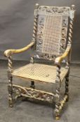 A walnut framed armchair in the Charles II manner with carved and pierced top rail featuring putto